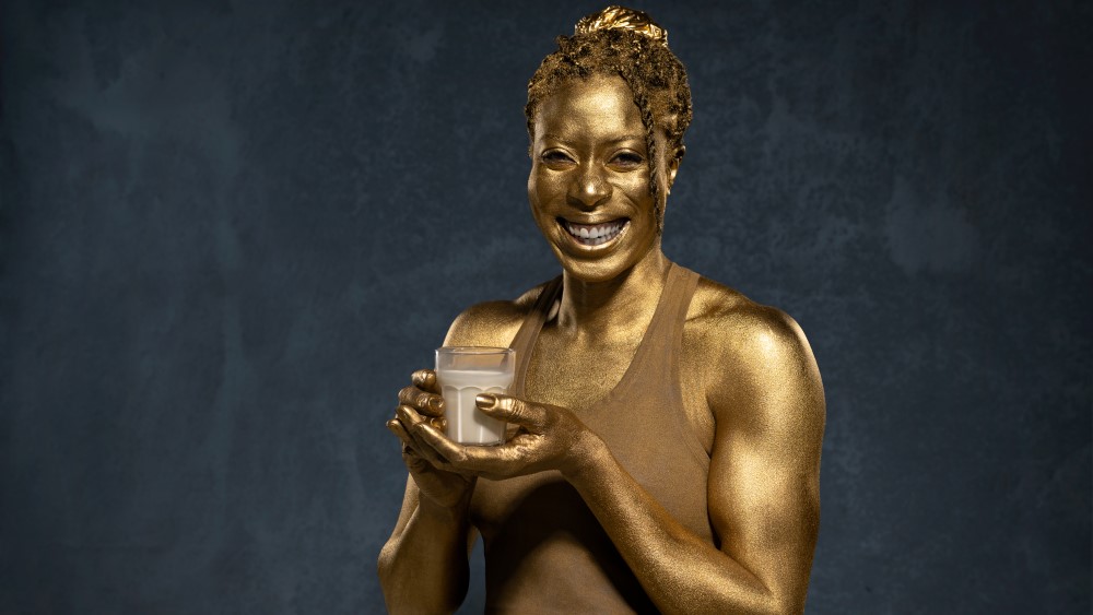 Christine Ohuruogu painted gold and holding a glass of milk
